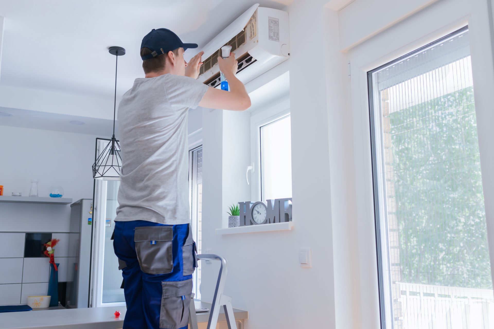 Técnico limpiando unidad de aire acondicionado en una sala